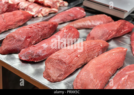 Asoortment di materie di filetto di manzo carne al mercato degli agricoltori. Contatore di metallo con molti grandi lastre di carni di vitello e di carne di maiale all'ingrosso negozio di macellaio. Foto Stock