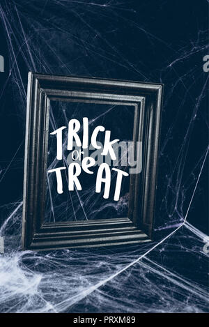 Telaio nero in spider web, creepy halloween decor con "dolcetto o scherzetto" scritte Foto Stock