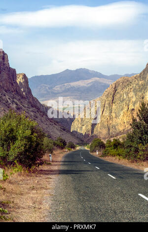 Una tortuosa strada che conduce verso il basso attraverso una profonda valle del fiume lontano dal monastero di Noravank immerso nella collina isolata, vicino Yeghegnador, Armenia. Foto Stock