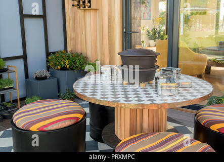 Balcone con sedie a tamburo in legno riciclato, cuscini, area pranzo esterna, patio, viole, succulenti e micro green UK Foto Stock