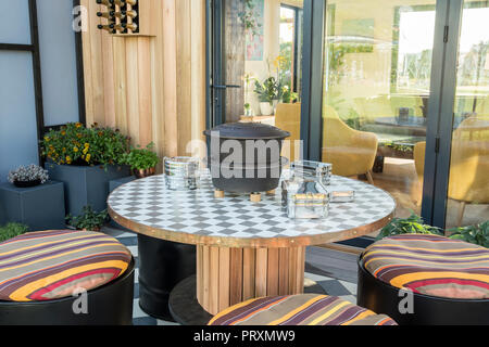 Balcone con tavolo e sedie in legno riciclato riadattato, cuscini, area da  pranzo esterna con patio, viole, succulenti e micro green UK Foto stock -  Alamy