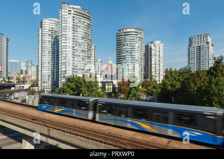 Lo Skytrain in movimento lungo le piste con la città di Vancouver come sfondo, Foto Stock