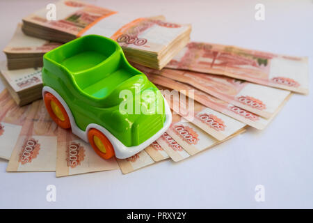 Prestito auto.Concetto di risparmi per comprare una macchina denaro.miniatura modello di auto nei pressi di denaro contante ,rubli russi, isolato su bianco. Commercio auto per contanti. Assicurazione e acquisto di concetto auto.spazio copia.Istruzione concetto di bilancio Foto Stock