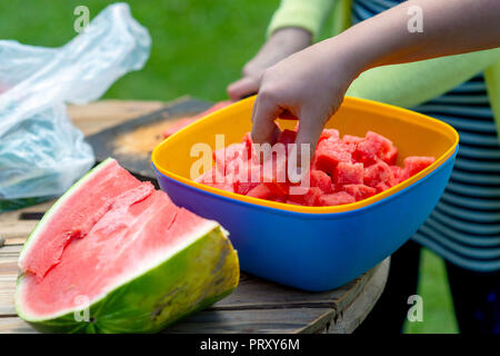 Una donna su una calda giornata offre pezzi tagliati a fette di cocomero. Foto Stock