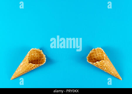 Creative layout estiva fatta di coni gelato, waffle coni luminosi su fondo azzurro. La minima nozione Foto Stock