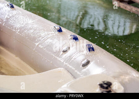 L'uomo bianco lavaggio barca gonfiabile con pennello e con acqua in pressione sistema a garage. Servizio nave e stagionali e un concetto di manutenzione. Foto Stock