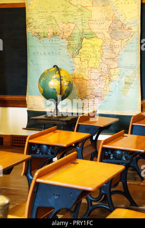 Banchi vuoti in aula scolastica con globo e la mappa. Foto Stock