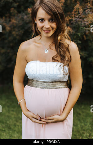 Ritratto di sorridere donna incinta mentre tiene il suo ventre Foto Stock