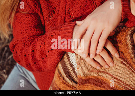 Woman in Red maglione tenendo le sue mani sulla spalla del suo uomo. Foto Stock