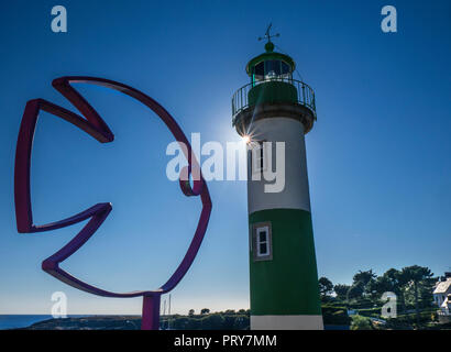 Faro e pesci scultura con rottura sole intorno al faro del porto di pesca di Doëlan, Clohars-Carnoët, Francia Finisterre Brittany Foto Stock