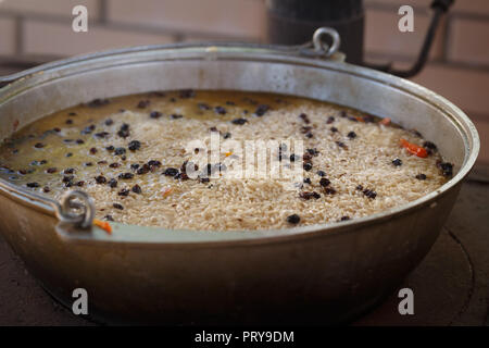 Fulvous riso, crespino e altri ingredienti dei deliziosi piatti asiatici sono pilaf cotta nel brodo di carne in grandi ghisa beck Foto Stock