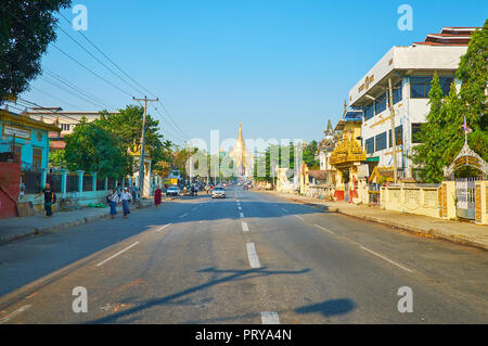 YANGON, MYANMAR - Febbraio 27, 2018: per raggiungere a piedi la Shwedagon pagoda lungo la trafficata Tawya Gyar street con molti monasteri buddisti e mercato locale Foto Stock