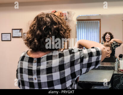 Donna di mezza età parrucchiere proprietario di taglio di capelli uomo senior; sia riflettere nello specchio Foto Stock