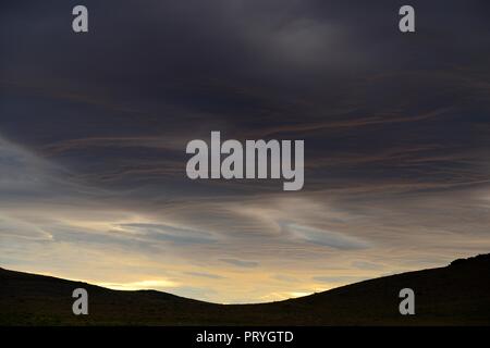 Tramonto spettacolare con crescente nuvole temporalesche nella parte anteriore del silhouette di montagna, Pali Aike National Park, Magallanes Provincia del Cile Foto Stock