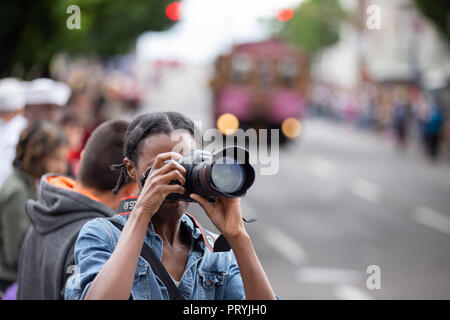 Portland, O / STATI UNITI D'America - 11 Giugno 2016: Grand sfilata floreale, americano africano fotografo femmina di scattare le foto con la Canon fotocamera reflex digitale. Foto Stock
