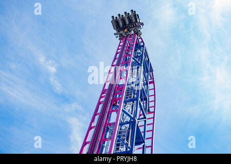 Carrello con le persone al picco del roller coaster contro il cielo blu Foto Stock