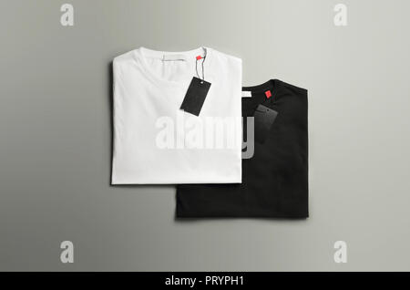 Elegante mockup di vestiti di bianco e di nero leggermente piegato due T-shirt su uno studio uno sfondo grigio. Mockup può utilizzare per la progettazione. Foto Stock