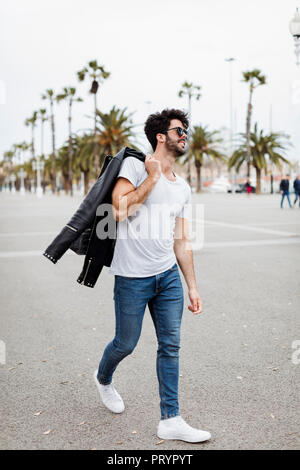 Spagna, Barcellona, giovane uomo a camminare sul lungomare con palme Foto Stock
