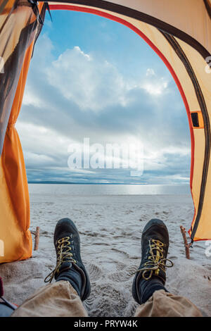 Piedi di uomo, giacente in tenda sulla spiaggia Foto Stock