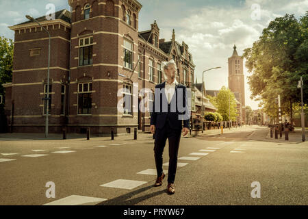 Paesi Bassi, Venlo, imprenditore a camminare su una strada con il sacchetto in plastica sopra la sua testa Foto Stock