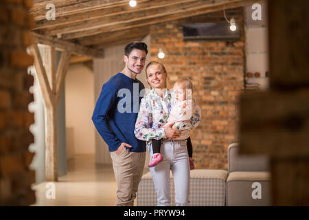Ritratto di felice giovani genitori con la loro bambina a casa Foto Stock