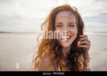 Ritratto di una donna redheaded, ridevano allegramente sulla spiaggia Foto Stock