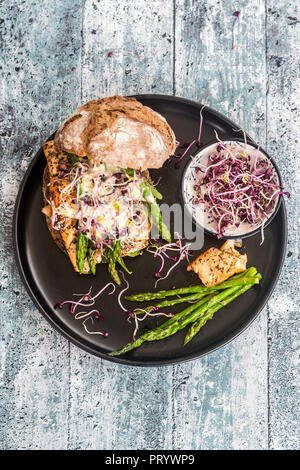 Hamburger di salmone con asparagi verdi e rosso il crescione su piastra Foto Stock