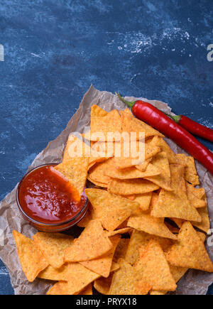 Messicano gustosa tortilla chips con salsa di pomodoro in salsa di blu scuro dello sfondo in calcestruzzo. Foto Stock