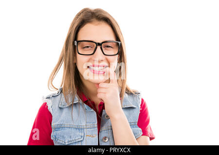 Affascinante giovane donna adolescente in bicchieri di mordere unghie e guardando giocosamente alla fotocamera su sfondo bianco Foto Stock