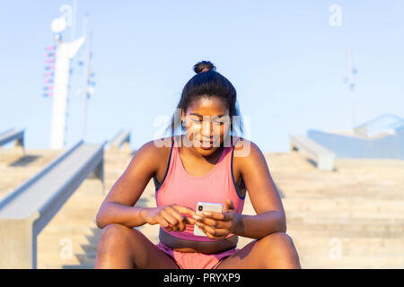 Giovane donna sportive utilizza lo smartphone Foto Stock