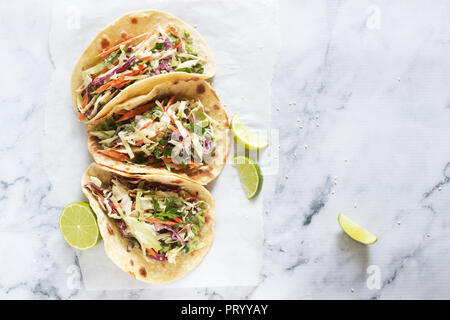 Tacos con il guacamole e coleslaw servita con fettine di lime su uno sfondo luminoso. Foto Stock