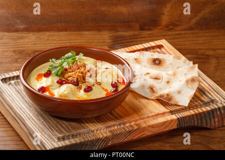 Satsivi con salsa di tacchino e noce - cucina tradizionale georgiana / armena. Servita in una ciotola su un tavolo di legno con pane affettato. Foto Stock