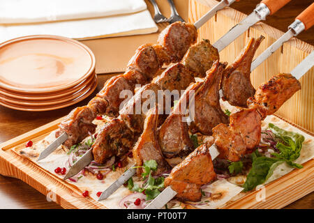 Khorovats- piatto tradizionale armeno Kebab/spiedini su tavola di legno. Spiedini di vitello, agnello, maiale e pollo serviti su pane piatto. Foto Stock