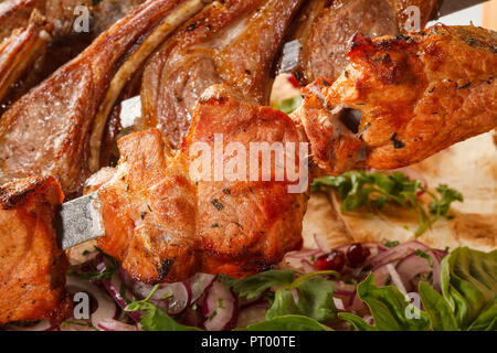 Khorovats- piatto tradizionale armeno Kebab/spiedini su tavola di legno. Spiedini di vitello, agnello, maiale e pollo serviti su pane piatto. Foto Stock