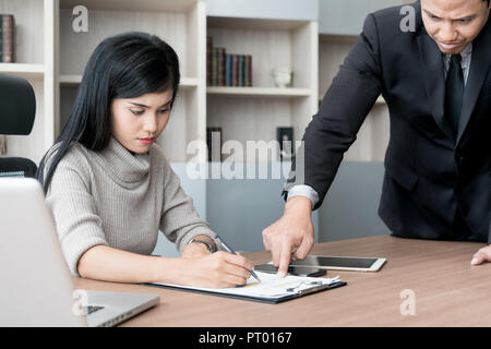 Segretario asiatica sottolinea quando il suo manager è il puntamento e viene imputato per un lavoro difettoso. Segretario e manager in ufficio. Foto Stock