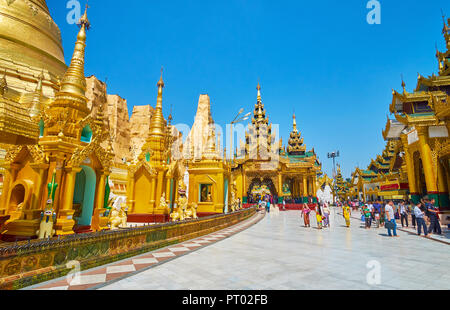 YANGON, MYANMAR - Febbraio 27, 2018: Lo stupa di Shwedagon pagoda complesso con il principale santuario orientale - Kakusandha immagine del Buddha di casa sulla distanza, Foto Stock