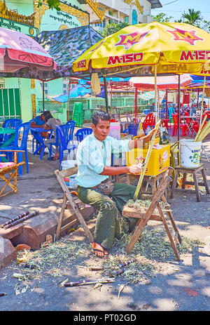 YANGON, MYANMAR - 27 febbraio 2018: Il venditore pela la canna da zucchero per la preparazione di succhi di frutta in Tawya Gyar street market, il 27 febbraio a Yangon. Foto Stock