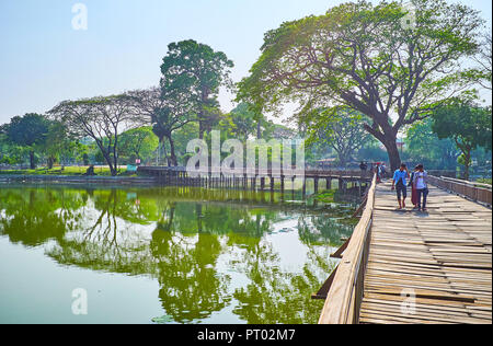 YANGON, MYANMAR - Febbraio 27, 2018: Lo scricchiolio traballante ponte di legno per attraversare il lago è l'attrazione locale di Kandawgyi park, il 27 febbraio in Ya Foto Stock