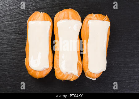 Eclairs con panna montata su sfondo nero. Foto Stock