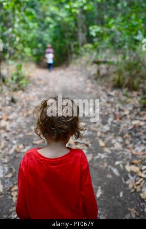 Un giovane bambino rosso da indossare a piedi attraverso una foresta, Dalrymple gap, QLD, Australia Foto Stock