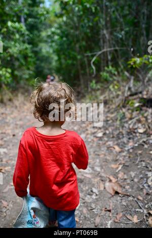 Un giovane bambino rosso da indossare a piedi attraverso una foresta, Dalrymple gap, QLD, Australia Foto Stock