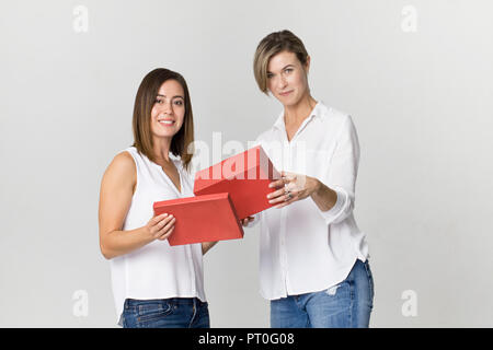 Sorpreso giovane donna riceve un regalo dal suo amico. Felice e sorridente amici di sesso femminile Foto Stock