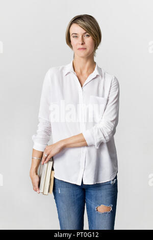 Giovani donne in camicia bianca e jeans con libri, isolato Foto Stock