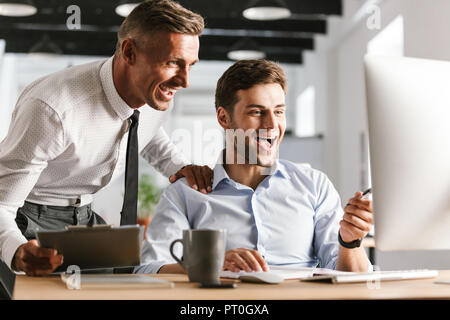 Foto di eccitazione emotiva felici uomini i colleghi in ufficio a lavorare con il computer. Foto Stock