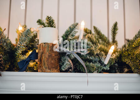 Natale camino, luci di Natale decorazione, rami di albero, candele e pezzi di pino Foto Stock