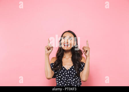 Immagine di felice giovane donna asiatica che posano su sfondo rosa rivolta verso l. Foto Stock