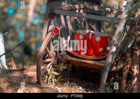 Piccolo vecchio carrello di legno in una foresta con un grande bicchiere di rosso e piattino sulla sommità di esso in una bella giornata di sole in autunno Foto Stock