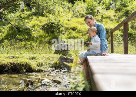 Madre e figlia seduti sul ponte di legno, Ruscello di montagna Foto Stock