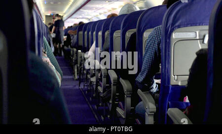 Candid shot tra i sedili dei passeggeri seduti all'interno aereo mentre si è in viaggio. Foto Stock