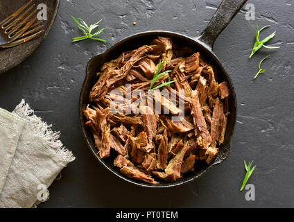 Lenta cottura Carne bovina italiana per i panini in padella sulla pietra nera dello sfondo. Vista superiore Foto Stock